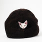 Small white kitten peeking out from a black cat bed on a white background | Natural, non‑toxic pet nest for cats and small dogs | Cozy, handmade pet furniture, natural wool and sheepskin


